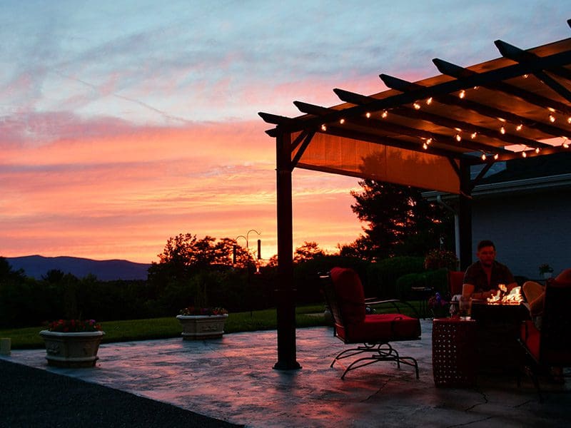 Friends sat by outdoor fireplace during sunset.