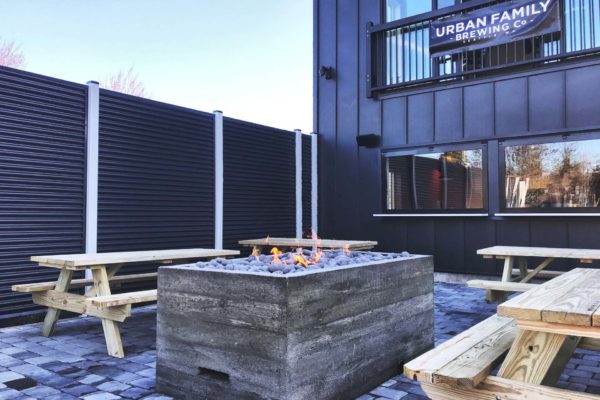 Outdoor fireplace for Urban Family Brewing Co surrounded by picnic tables.