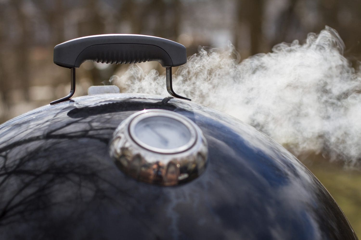 A close up of smoke coming from the The Weber Smokey Mountain charcoal smoker in the 14" size