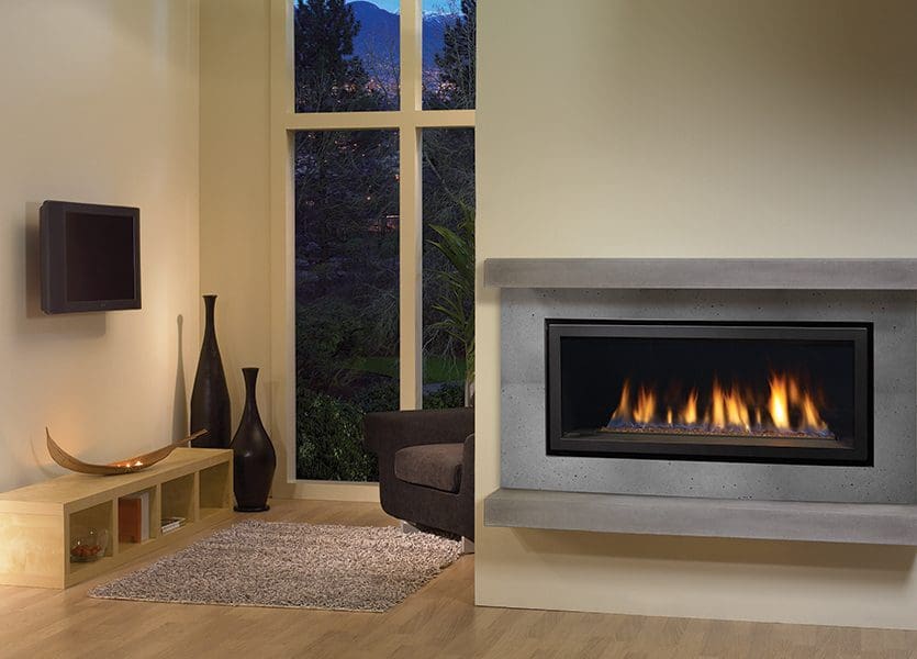 The Regency Horizon HZ40E Gas Fireplace in a grey stone exterior with a small bench in a living room with one chair