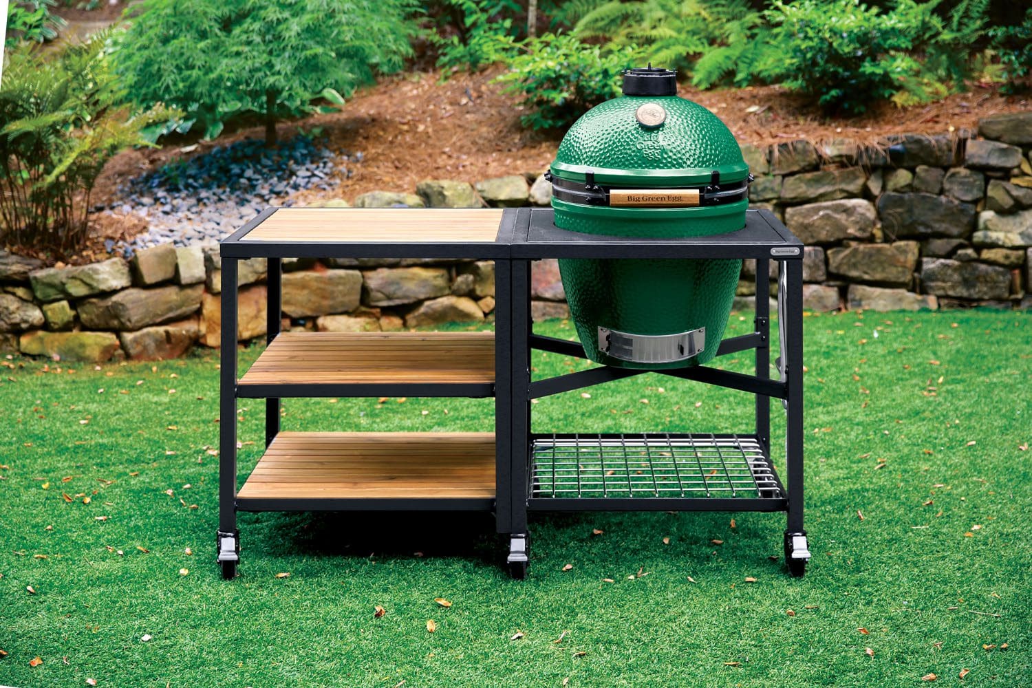 The Big Green Egg Large ceramic smoker pictured in the modular nest with acacia wood shelves