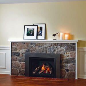 Picture of a rustic stone fireplace with a Valor G4 gas insert featuring traditional oak logs and a versatile iron gray trim