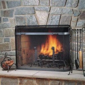 Freestanding fireplace spark guard screen in front of a traditional brick wood burning fireplace