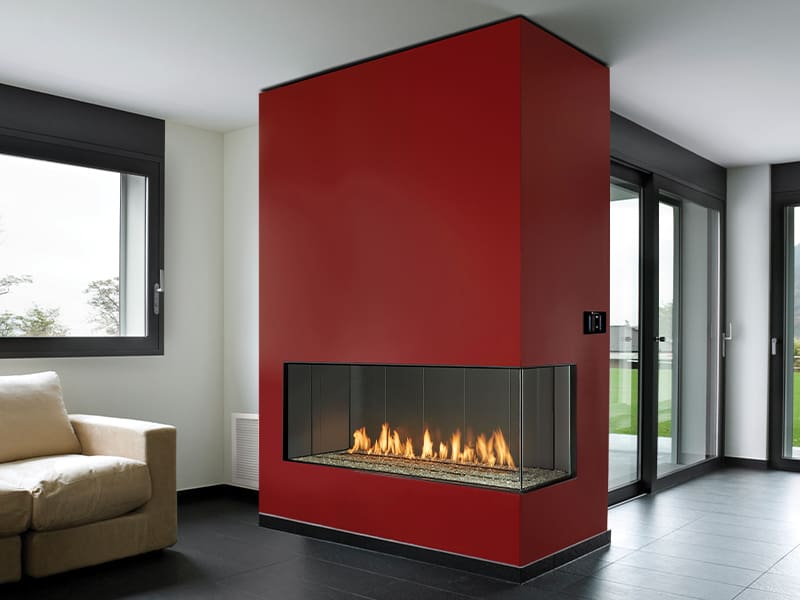 A modern living room features a Firenze™ Collection by DaVinci Custom Fireplaces™ centerpiece, black tile floors, large windows, and a beige sofa in the corner.